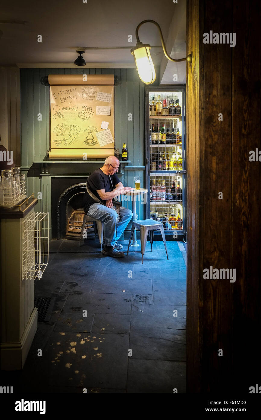 Un cliente solitario sentado en el interior de la casa pública Wheatsheaf en mercado de Borough. Foto de stock