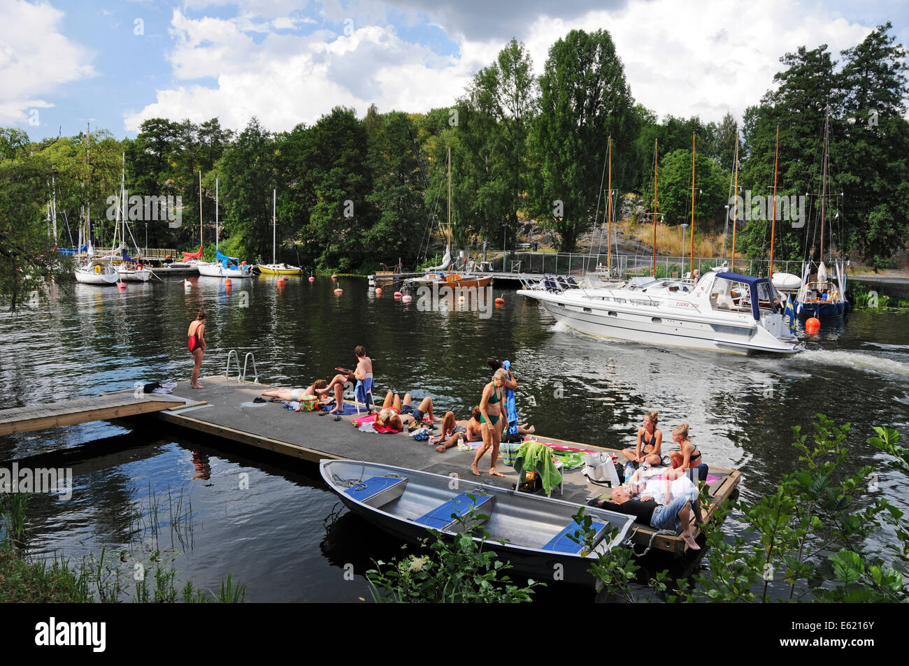 Barcos de excursión y kayakistas de Langholmen Långholmen Canal con bañistas en Estocolmo Foto de stock