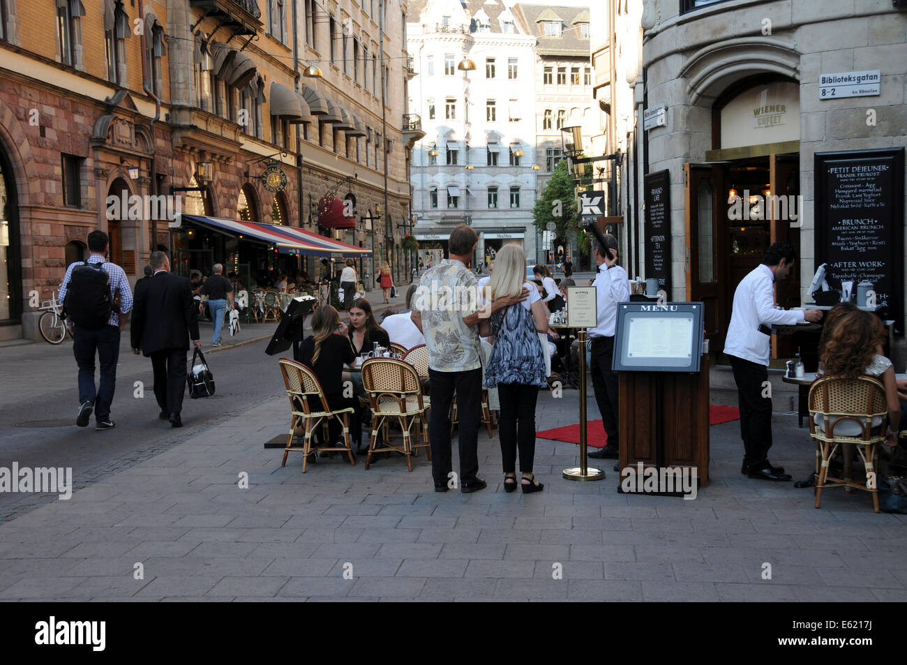 La vida en la calle en el casco antiguo de Estocolmo, con restaurantes, tiendas de café en la acera, los peatones y músicos a lo largo de calles adoquinadas Foto de stock