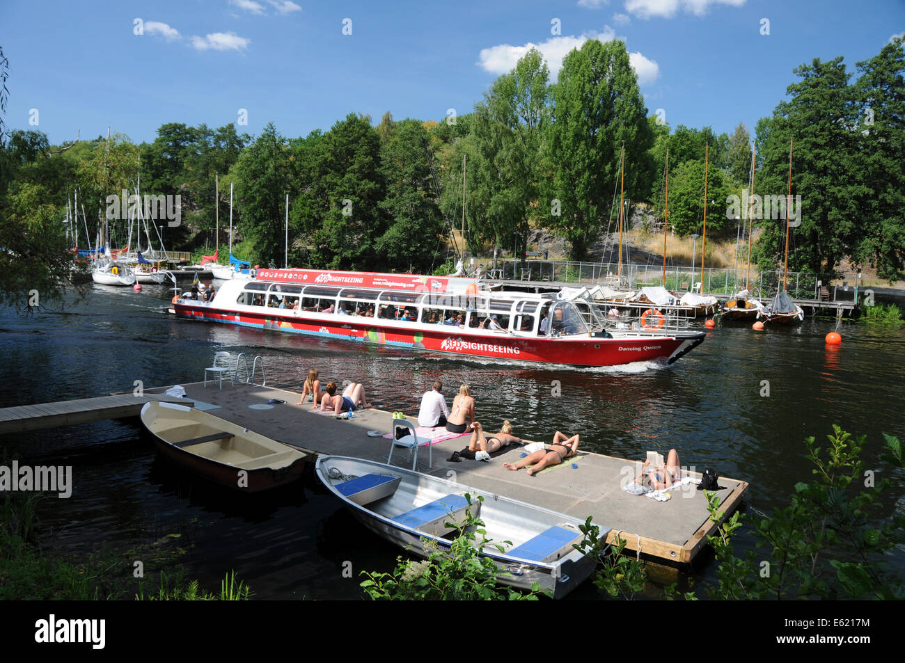Barcos de excursión y kayakistas de Langholmen Långholmen Canal con bañistas en Estocolmo Foto de stock