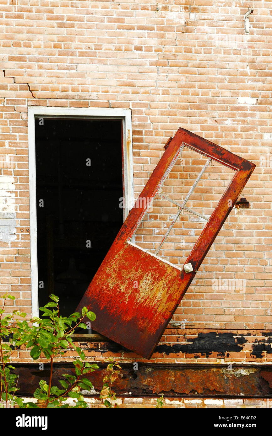 Una oxidada puerta sacándola de sus bisagras en un edificio abandonado en Galveston, Texas, USA. Foto de stock