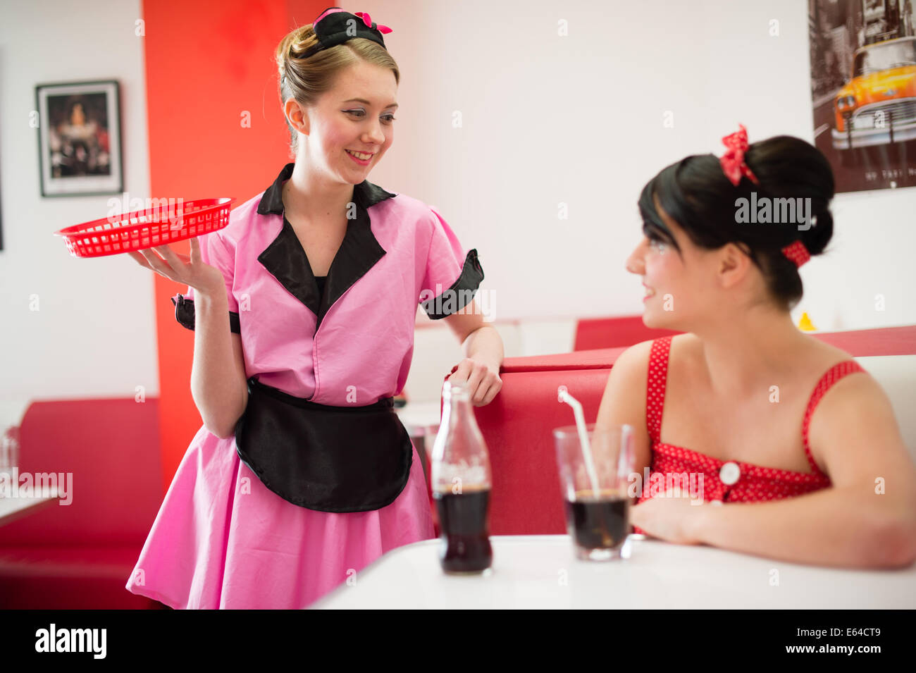 Una camarera vestida de 1950 estilo retro de moda ropa americana sirviendo  una clienta en un diner UK Fotografía de stock - Alamy