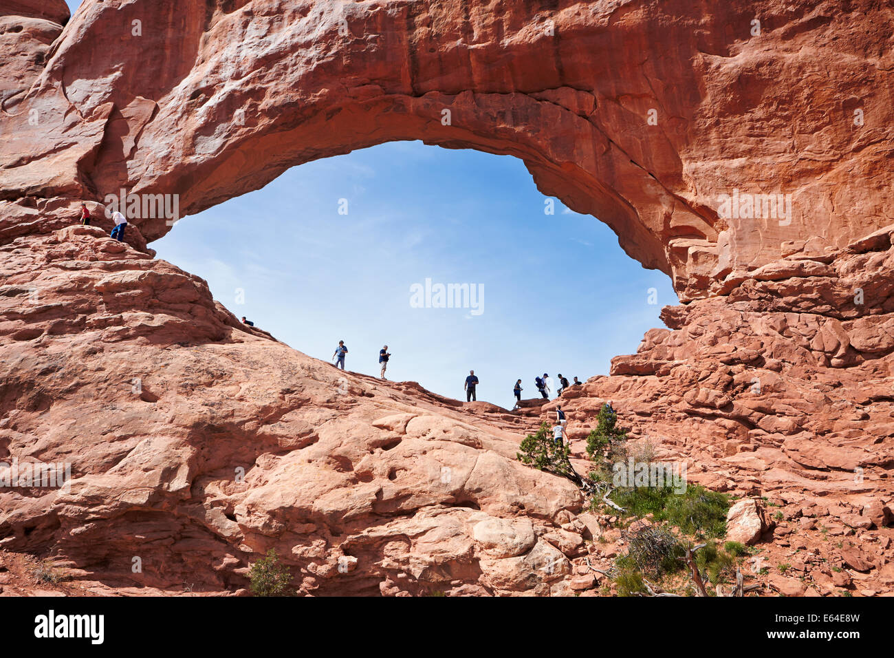 Los turistas se encuentran en el Arco de la ventana Norte. Parque Nacional Arches, Utah, EE.UU. Foto de stock