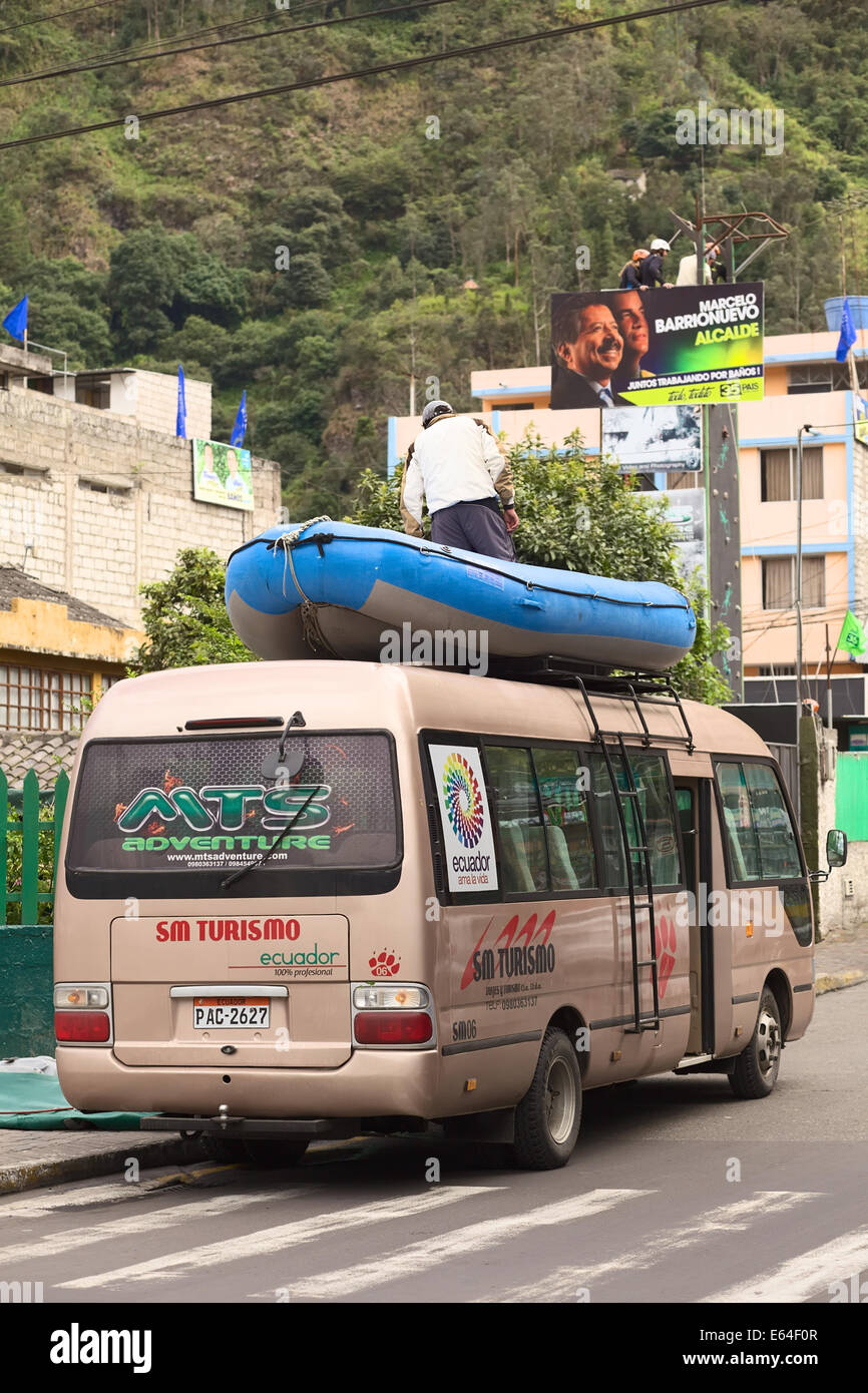 BANOS, ECUADOR - 25 de febrero de 2014: la persona no identificada de pie en un bote de goma atado a la baca de un minibús Foto de stock