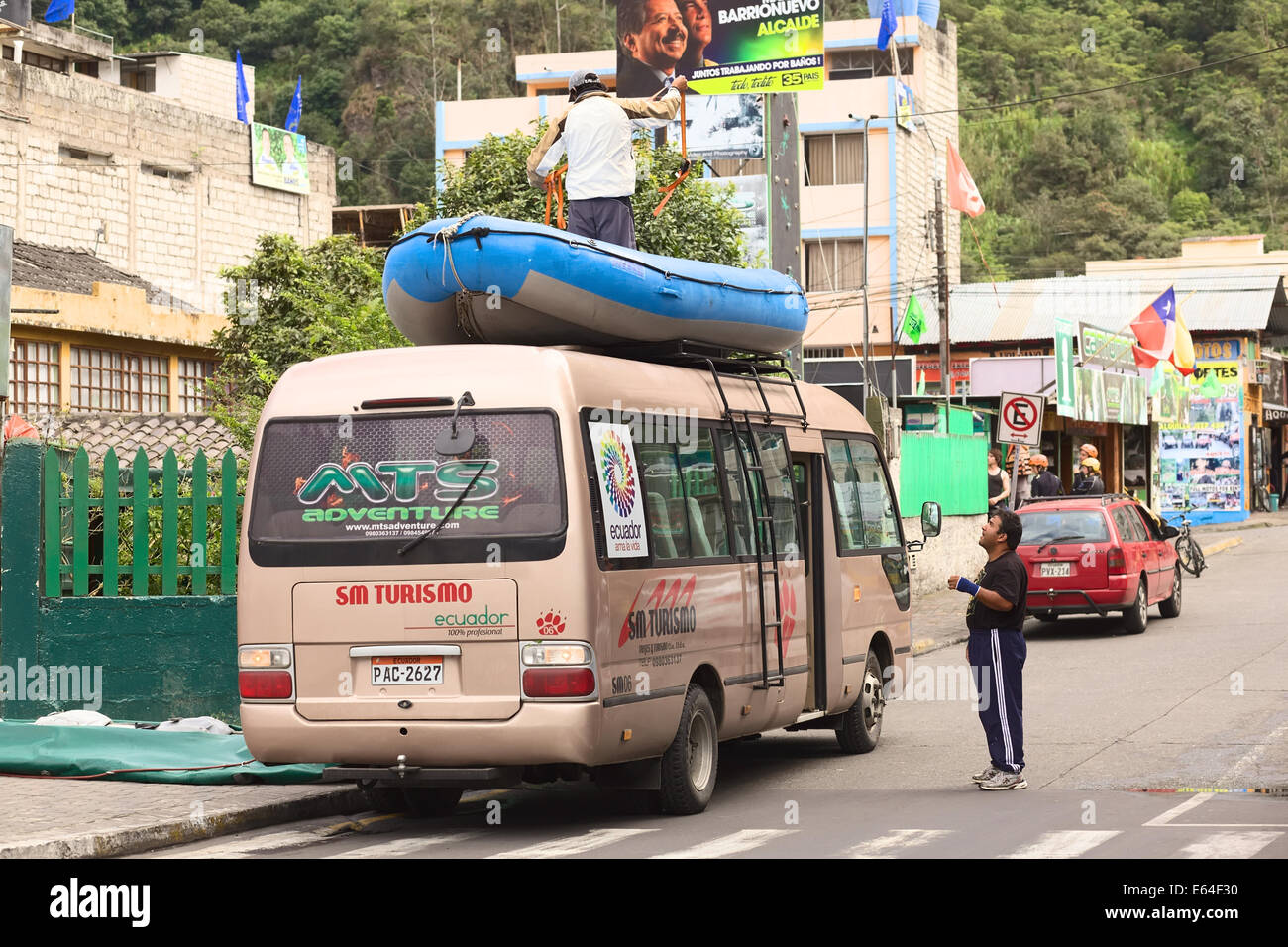 BANOS, ECUADOR - 25 de febrero de 2014: la persona no identificada de pie en un bote de goma atado a la baca de un minibús Foto de stock