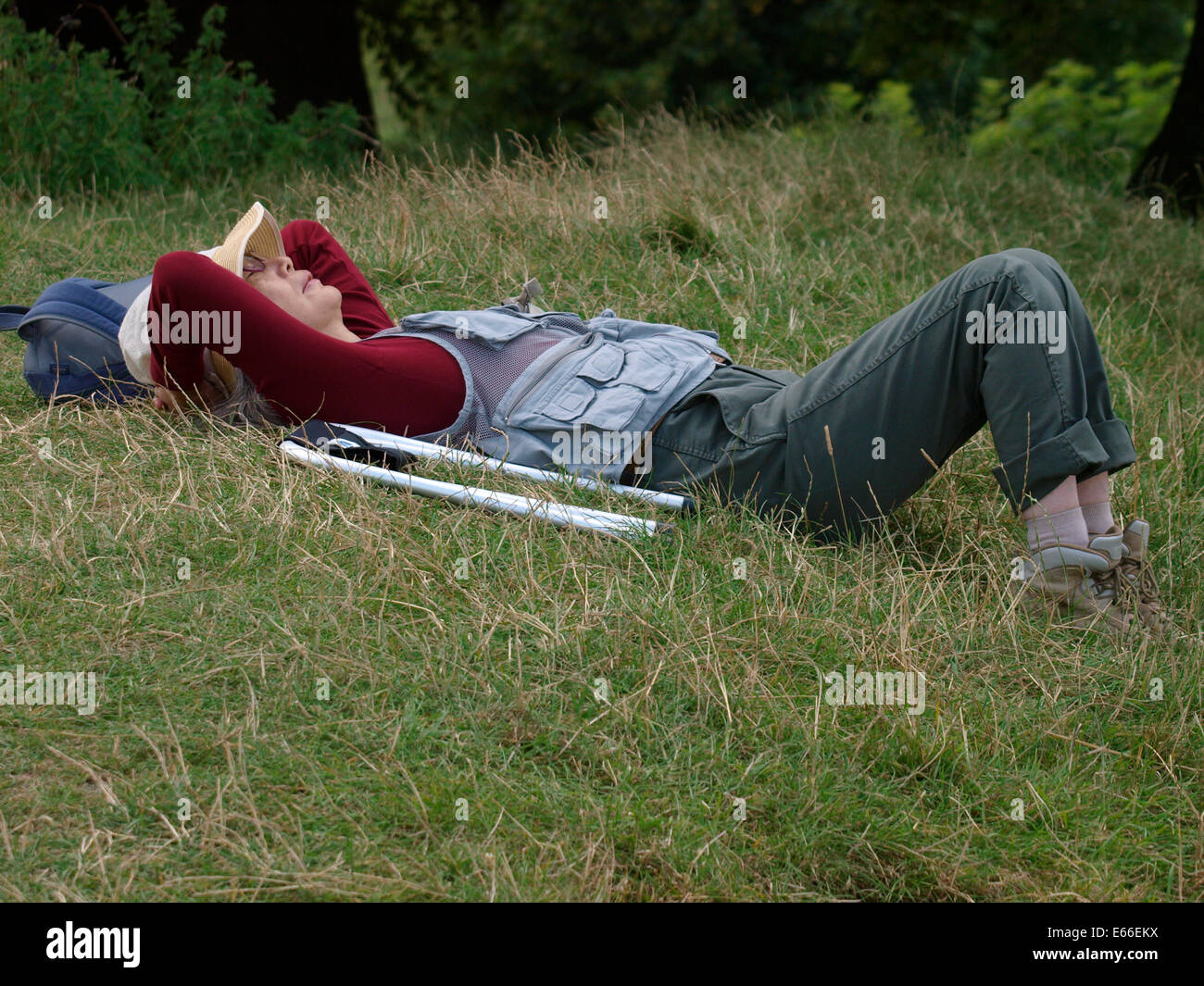 Mujer Asiática teniendo una siesta en el pasto en Avebury, Wiltshire, UK Foto de stock
