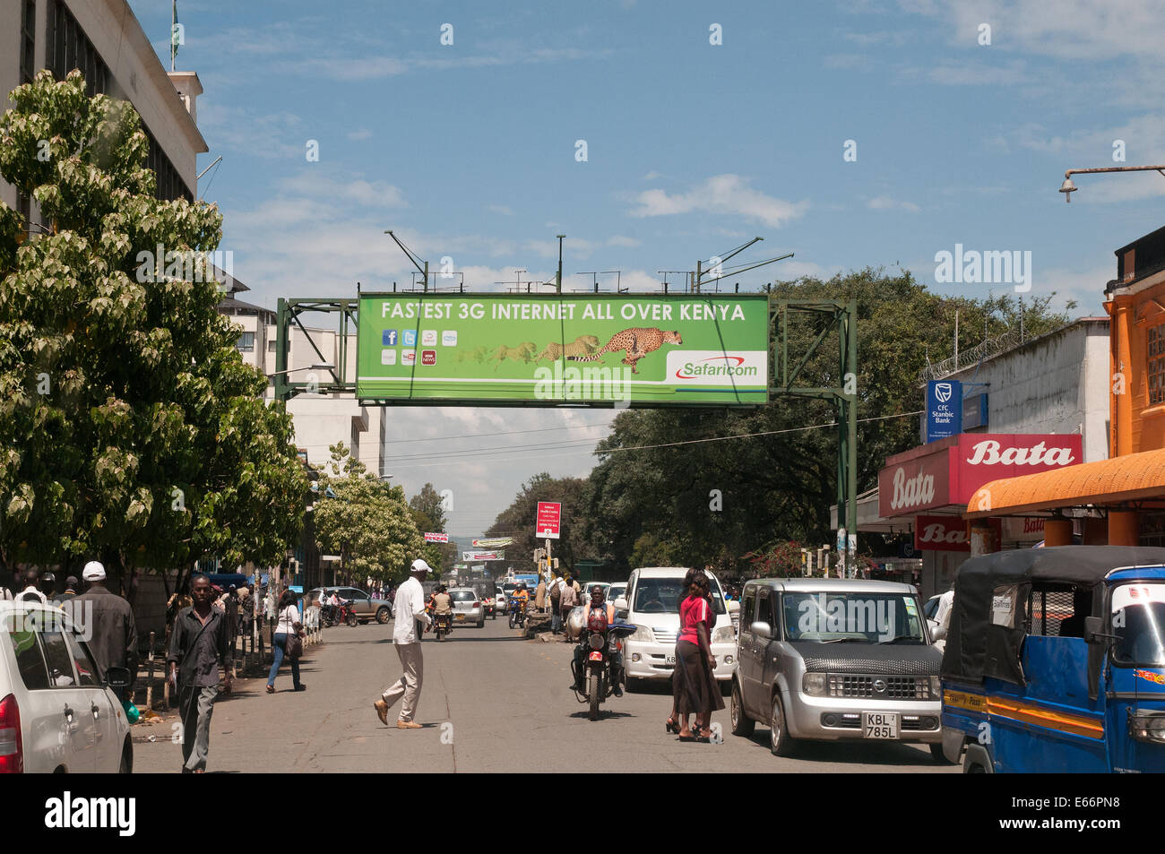 La gente y el tráfico en la avenida Kenyatta Nakuru, Kenya África oriental con el acaparamiento de publicidad para red 3G Foto de stock
