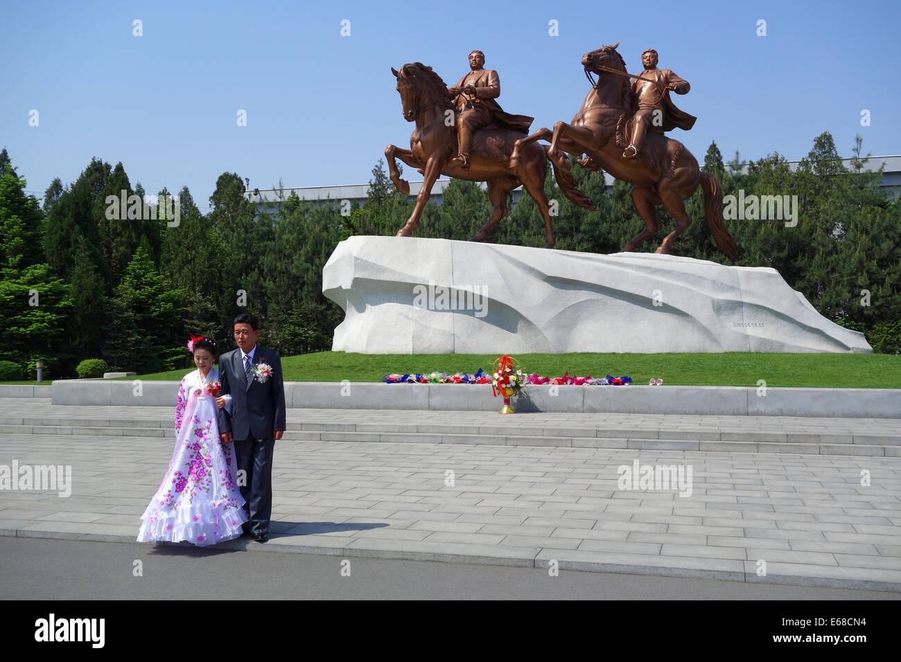 La novia y el novio delante de la estatua de grandes líderes Kim Il Sung y Kim Jong-il, Pyongyang, Corea del Norte Foto de stock