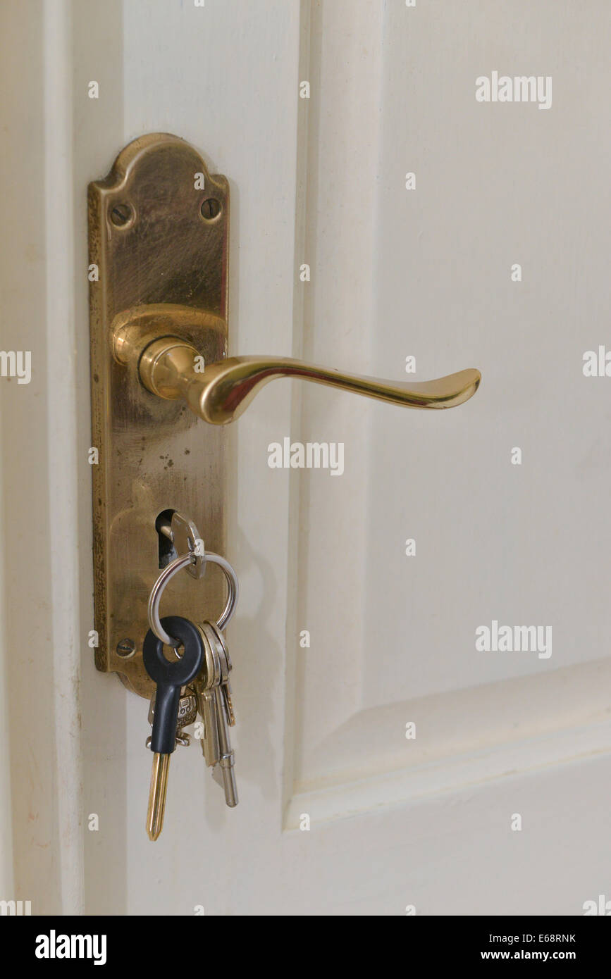La manija de la puerta con un manojo de llaves en la cerradura de una puerta blanca Foto de stock