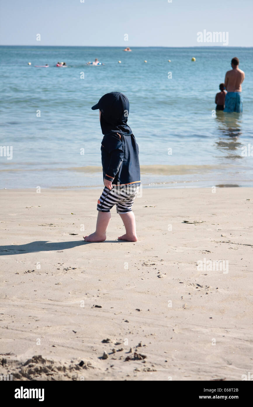 Un año de viejo muchacho caminando en una playa en La Trinité-sur-Mer, Bretaña, Francia Foto de stock