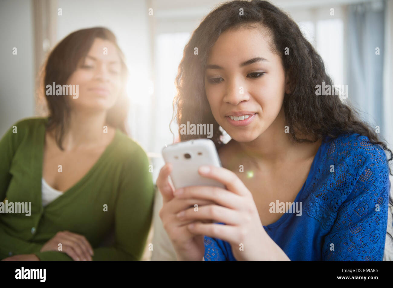 Madre Hija viendo utilizar teléfono celular Foto de stock