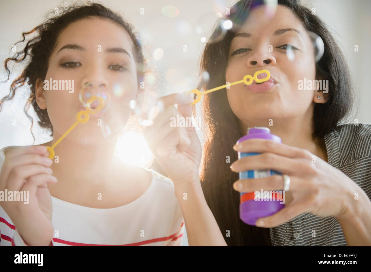 Madre e hija soplando burbujas juntos Foto de stock