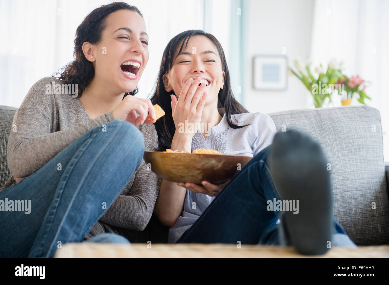 Las mujeres riendo juntos en el sofá Foto de stock