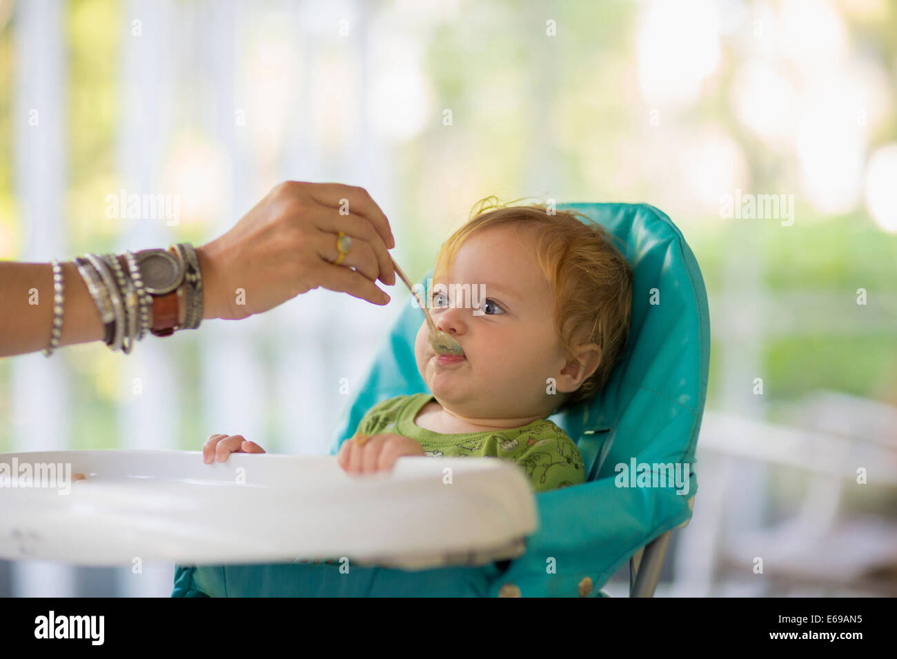 Caucasian madre alimentando a bebé en silla alta Foto de stock