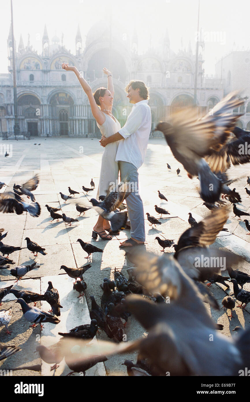 Par rodeada por palomas en la Plaza de San Marcos, en Venecia, Véneto, Italia Foto de stock