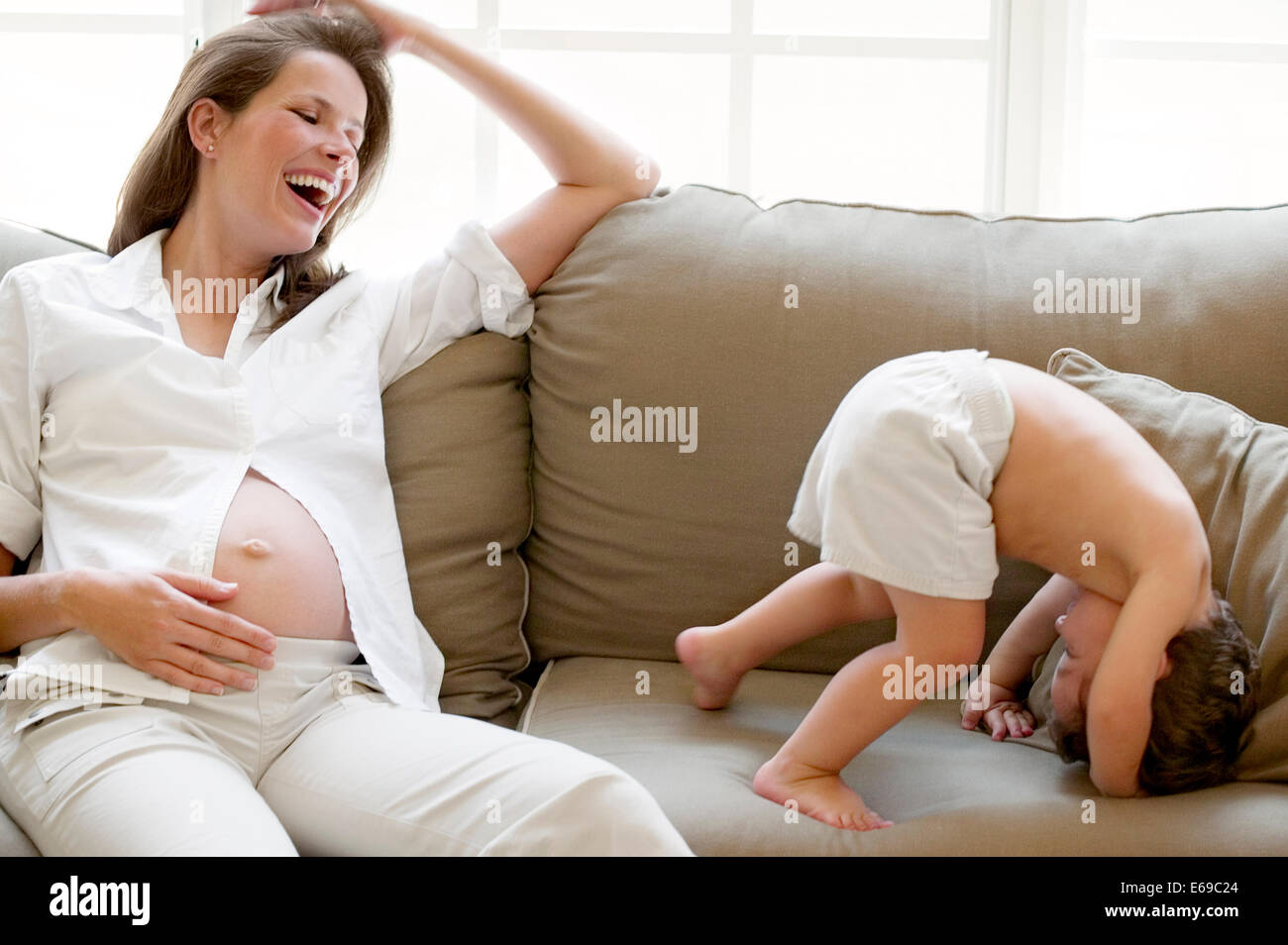 La madre embarazada y su hijo jugando en el sofá Foto de stock