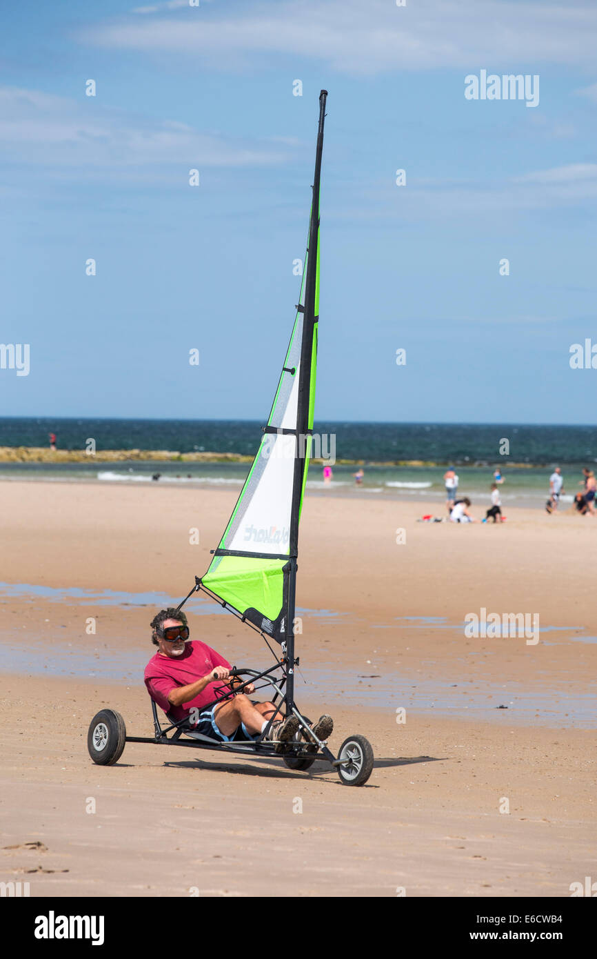 Un hombre en un yate de arena en la playa de Bamburgh en Northumberland, Reino Unido. Foto de stock