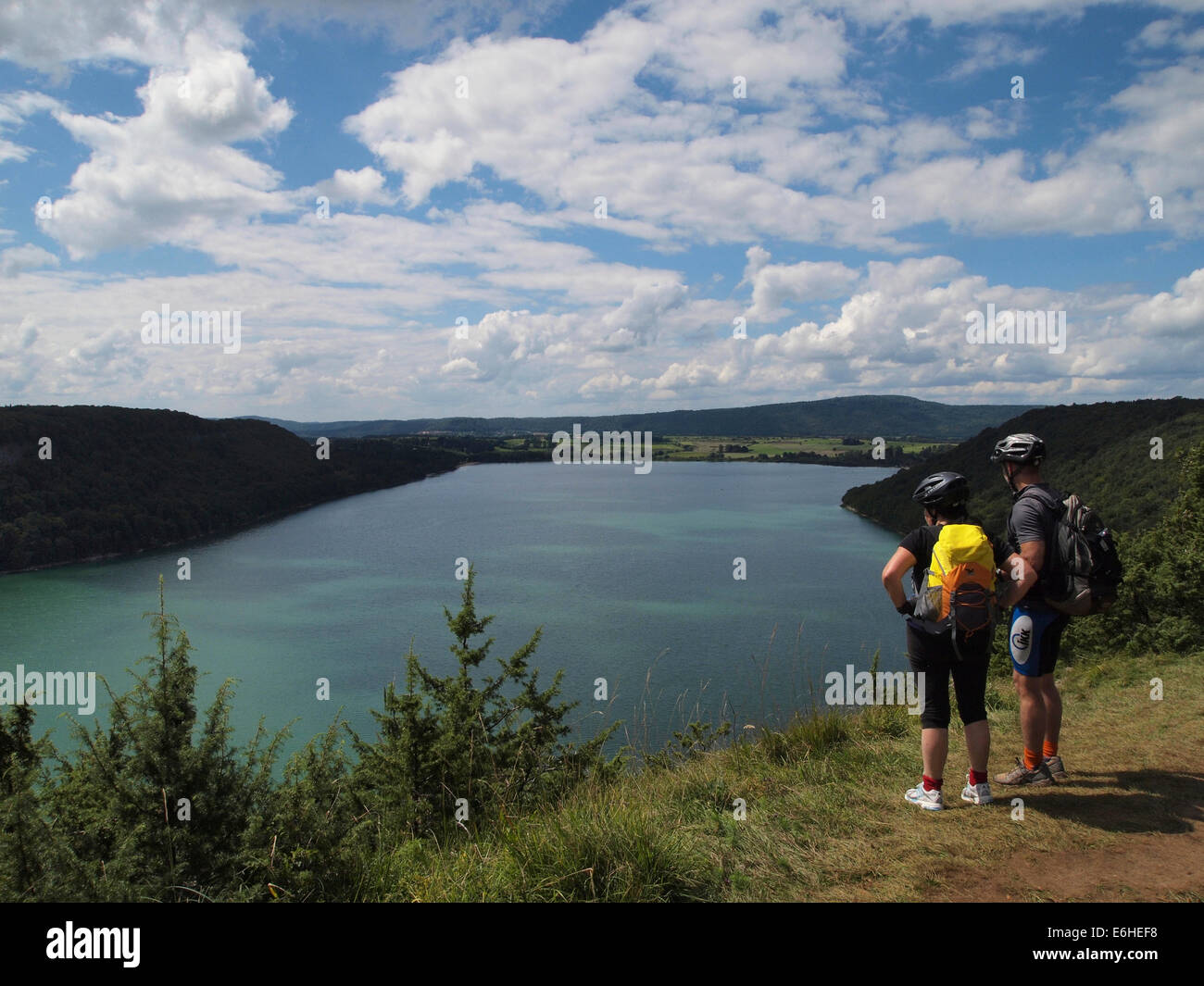 Dos ciclistas de montaña tomando un descanso con vistas a Lac de Chalain, Jura, Francia Foto de stock