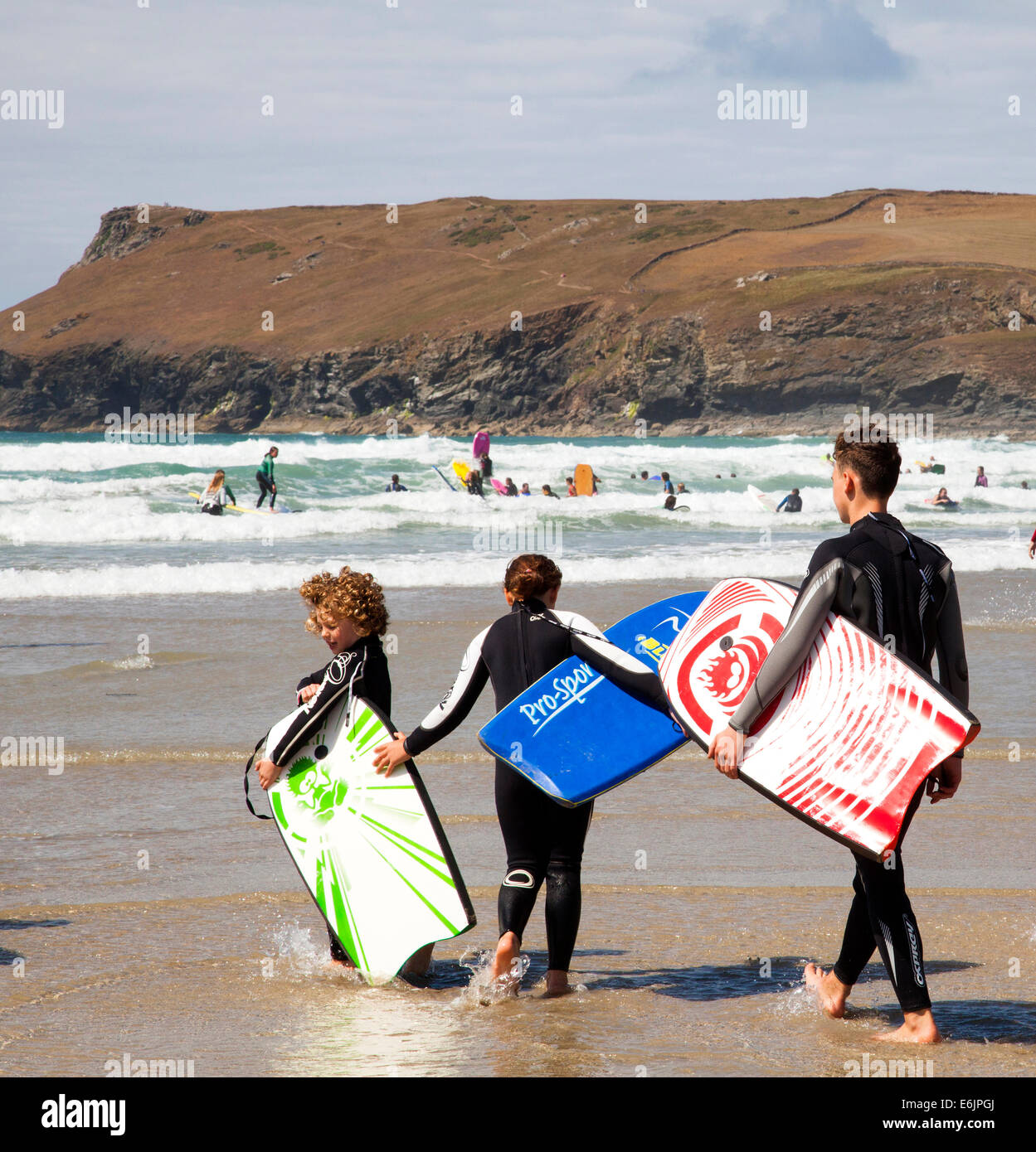 Una familia con body boards en Polzeath Playa, Cornwall, Inglaterra, Reino Unido. Foto de stock