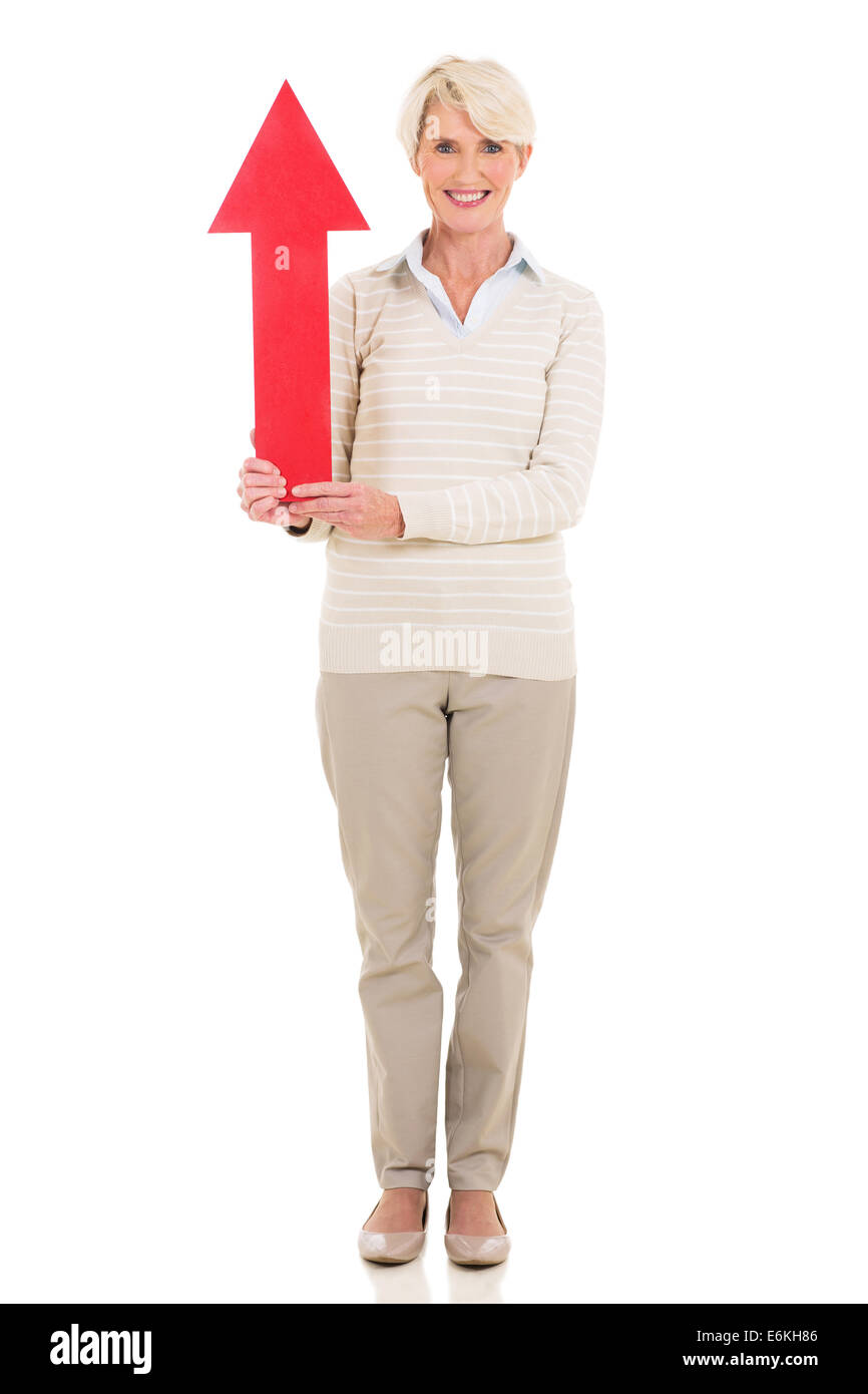 Bonita mujer de mediana edad la celebración de flecha roja apuntando hacia arriba Foto de stock