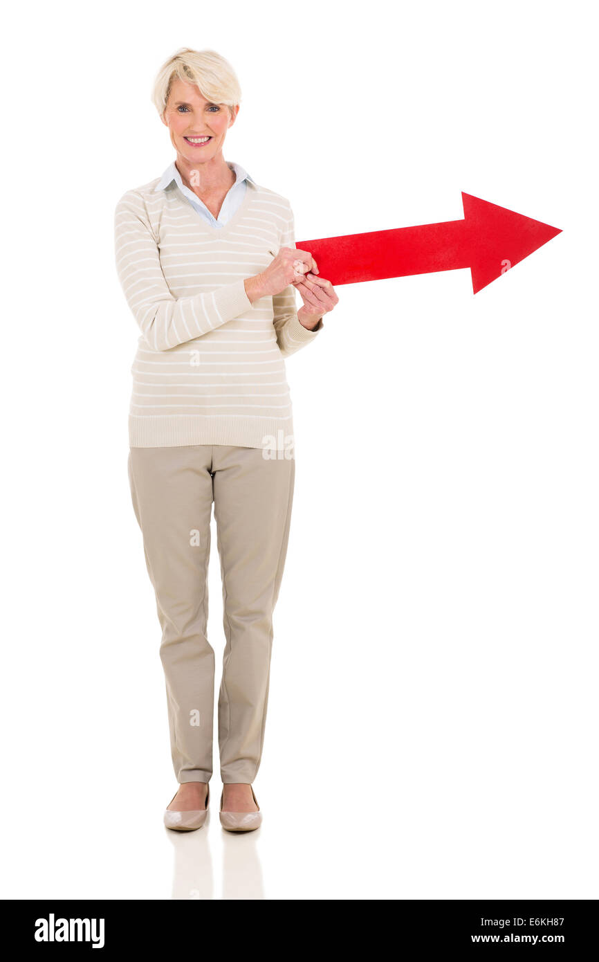 Mujer de mediana edad mantiene la dirección de la flecha grande sobre fondo blanco. Foto de stock