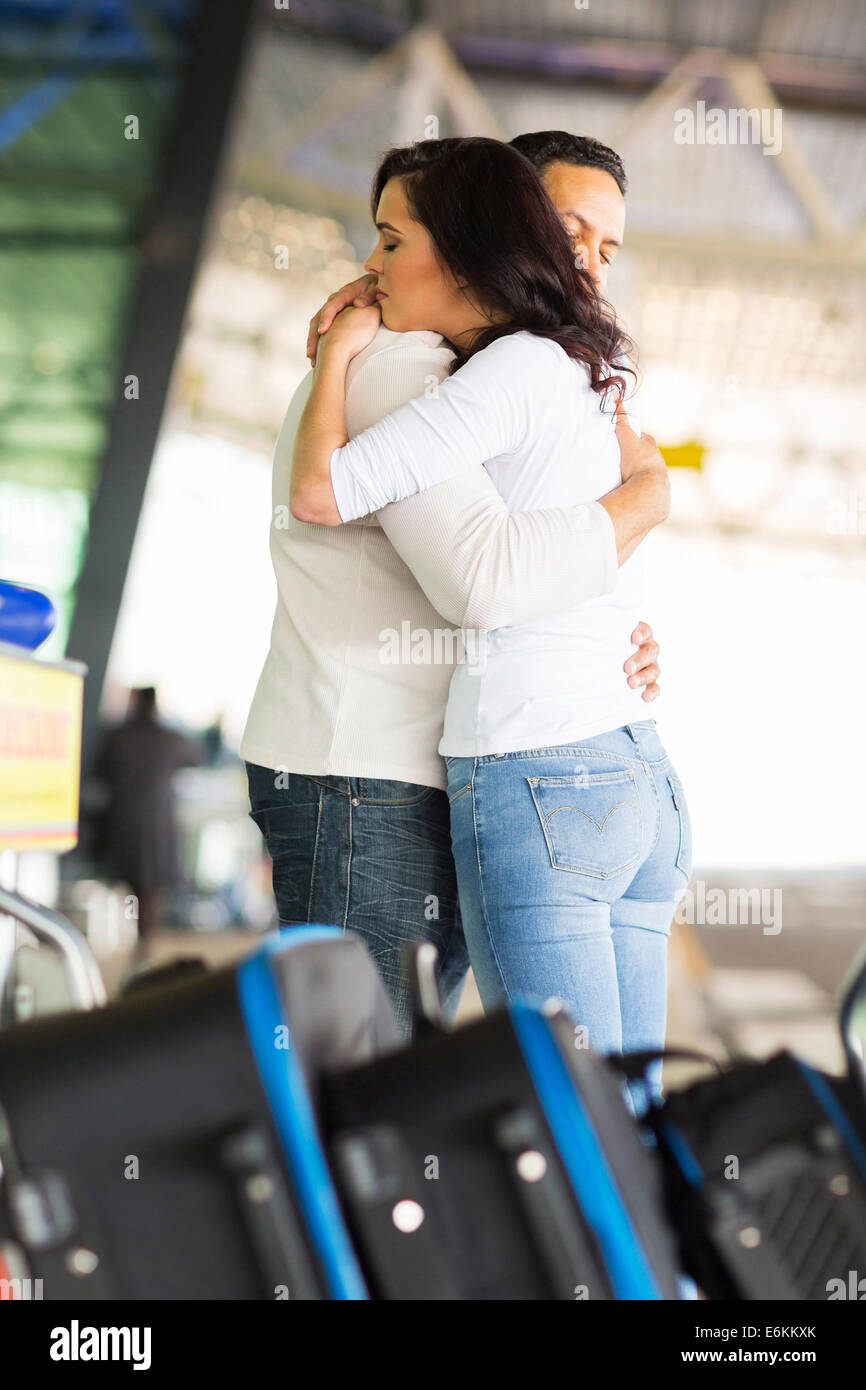 Pareja amorosa abrazando profundamente antes de despedida en el aeropuerto Foto de stock