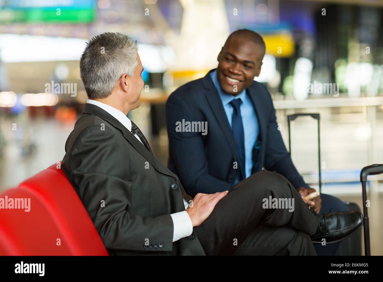 Socios de negocio feliz esperando en la sala de espera de aeropuerto Foto de stock