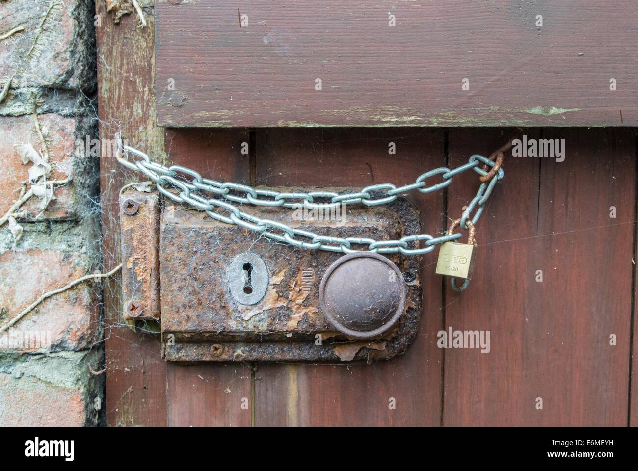 Cerradura de puerta oxidada con cadena adicional. Foto de stock