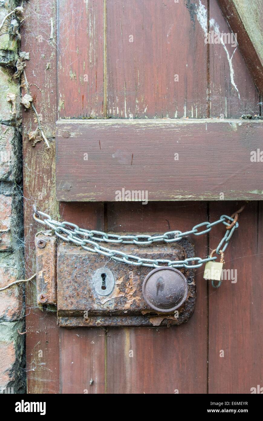 Cerradura de puerta oxidada con cadena adicional. Foto de stock