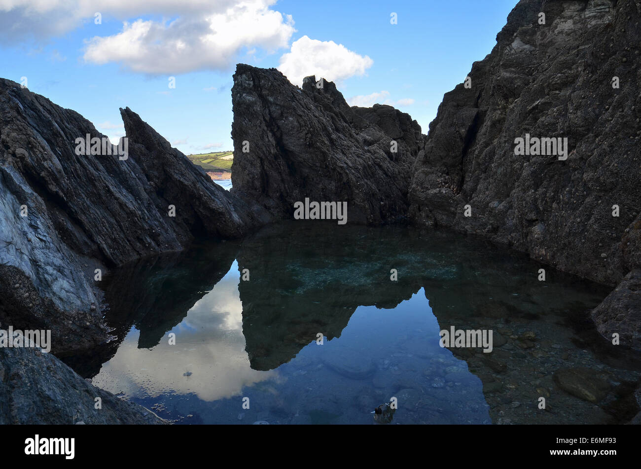 Afiladas rocas reflexión en una playa de Mothecombe rockpool en Devon. Foto de stock