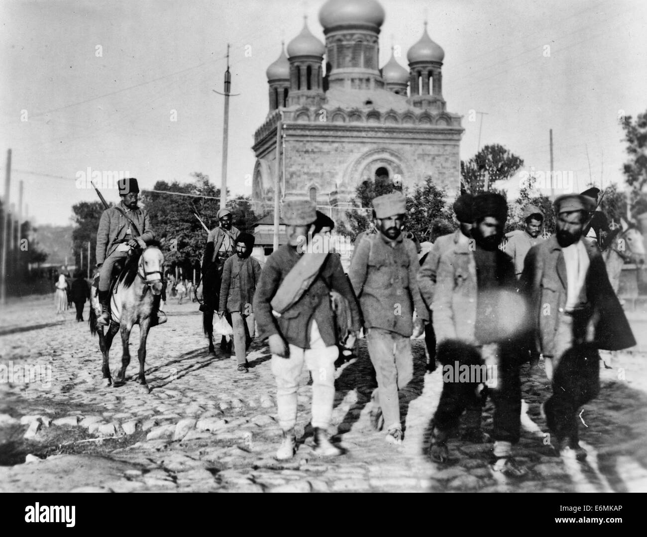 Los soldados armenios en traer un montón de prisioneros, estos hombres eran desertores del ejército de Armenia - Resumen: hombres caminando delante de los soldados a caballo en una calle de adoquines; iglesia de fondo. Octubre de 1919 Foto de stock