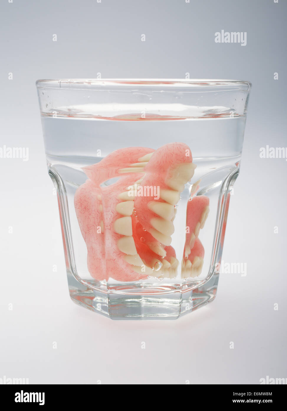 Una dentadura postiza en un vaso de agua sobre un fondo blanco Fotografía  de stock - Alamy