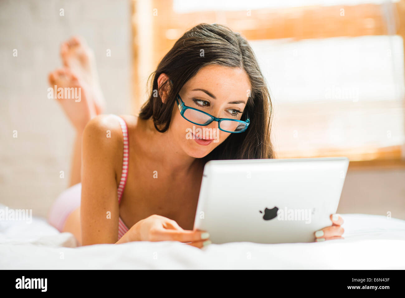 Una sexy mujer delgada con gafas en su ropa interior con iPad para enviar  emails leer Facebook surf web Snapchat en dormitorio UK Fotografía de stock  - Alamy