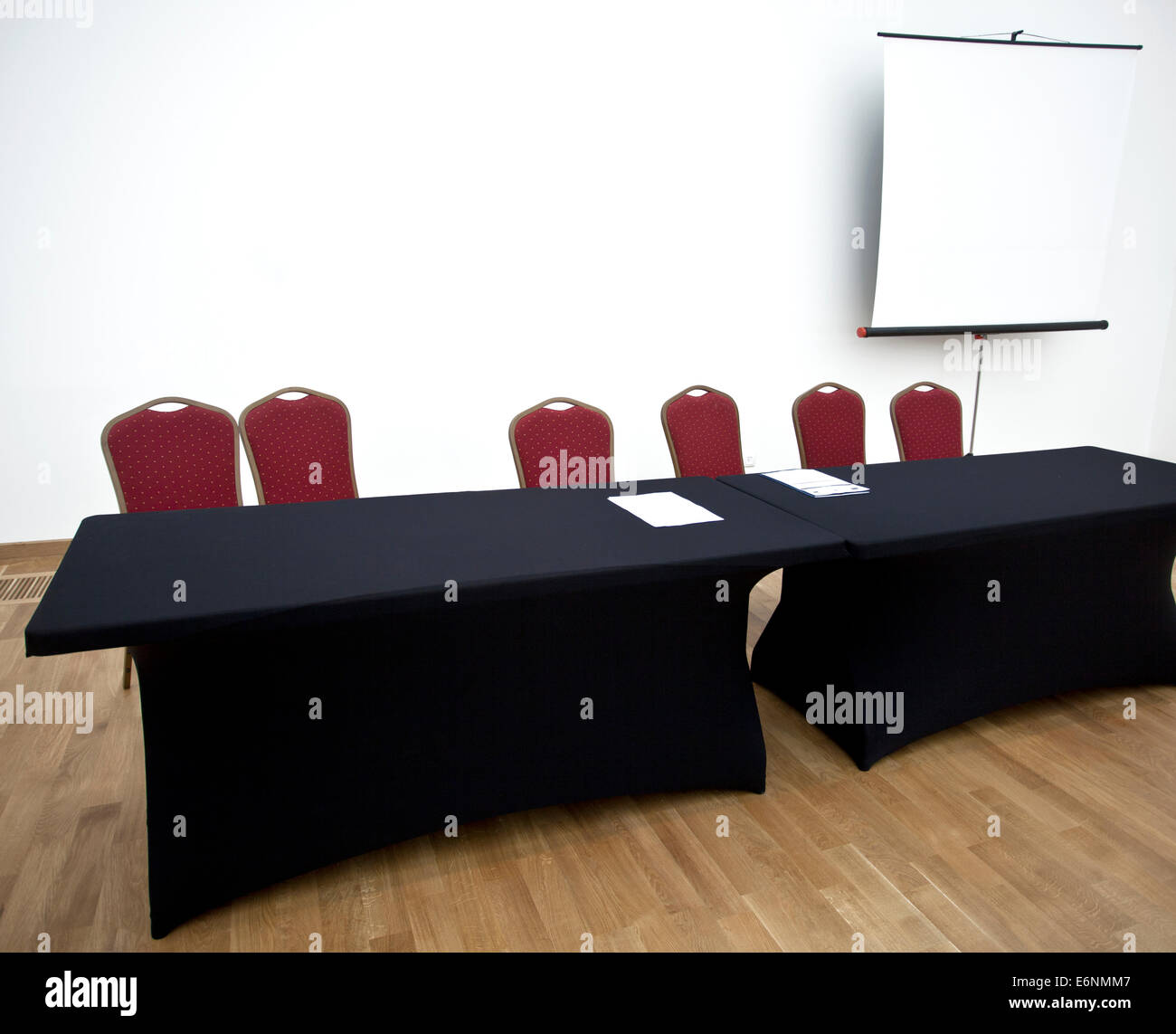 Sillas rojas, negras tablas y pantalla en la sala de conferencias vacía. Foto de stock