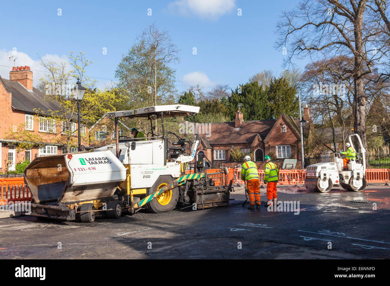 El mantenimiento de las carreteras. La terminadora, carretera de rodillo y los trabajadores de caminos trabajando en la repavimentación de carreteras en una calle de la aldea, Nottinghamshire, Inglaterra, Reino Unido. Foto de stock