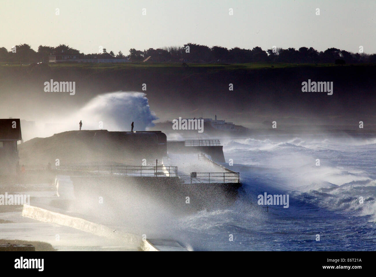 Hombre mirando a la energía de la tormenta de invierno surf golpeando la Muralla del Atlántico en la isla de Jersey durante el invierno de 2013 Foto de stock