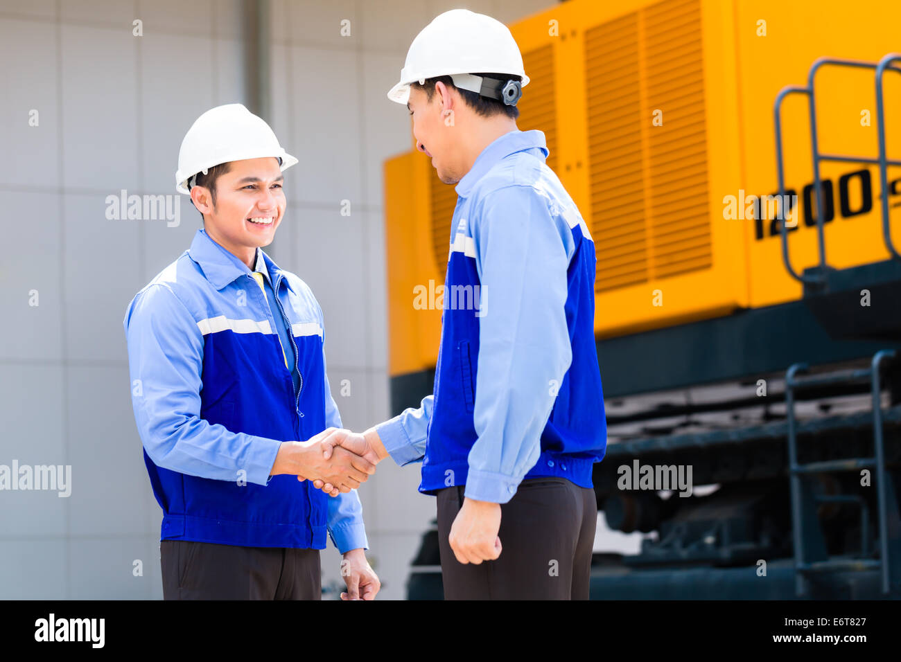 Ingeniero de Asia habiendo acuerdo apretón de manos en maquinaria de construcción de la obra o de la empresa minera Foto de stock