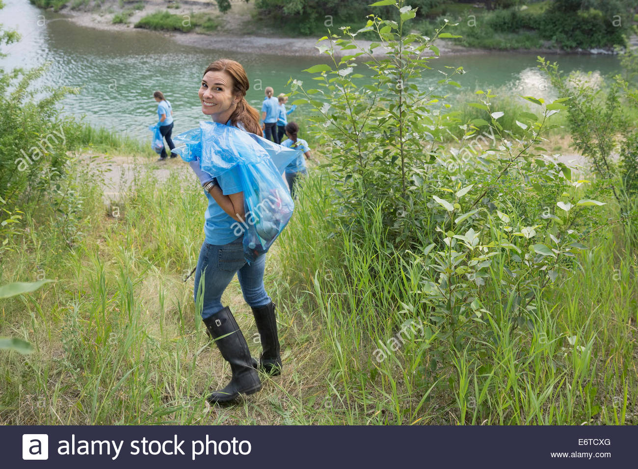 Retrato de sonriente voluntario llevar bolsa de basura Foto de stock