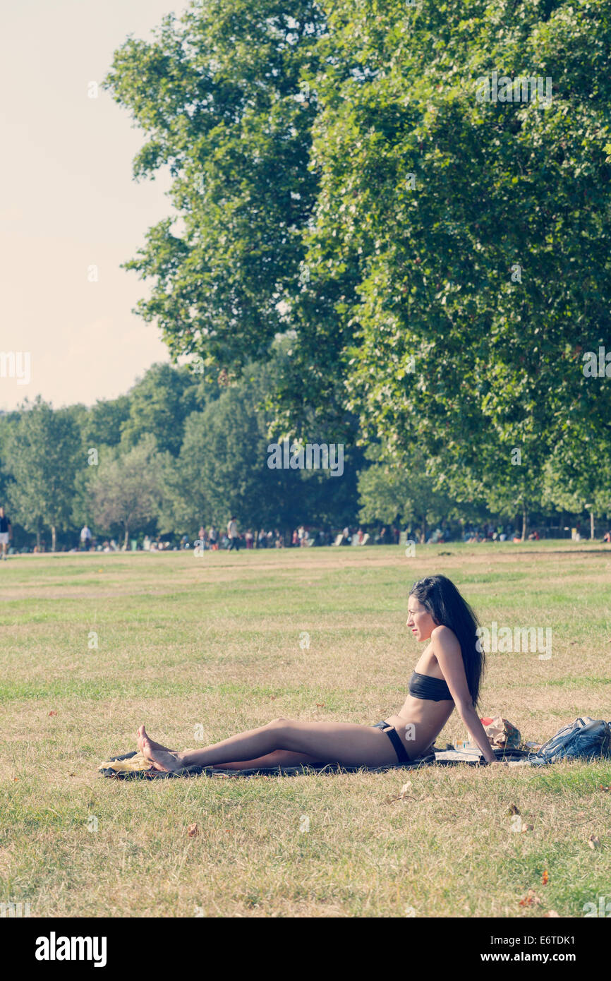 Una joven mujer de baños de sol en Hyde Park, Londres Foto de stock