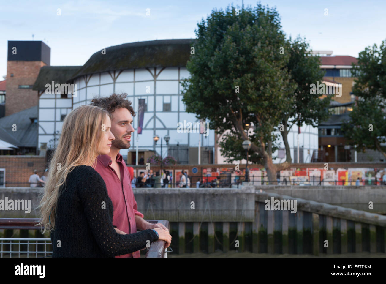 Una joven pareja de pie en frente del teatro Shakespeare's Globe Theatre en Londres Foto de stock