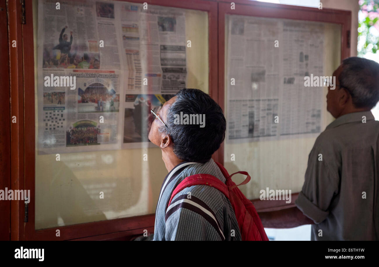 Yogyakarta, Java, Indonesia. La lectura de prensa diaria, publicado en vitrinas a la vista del público. Foto de stock