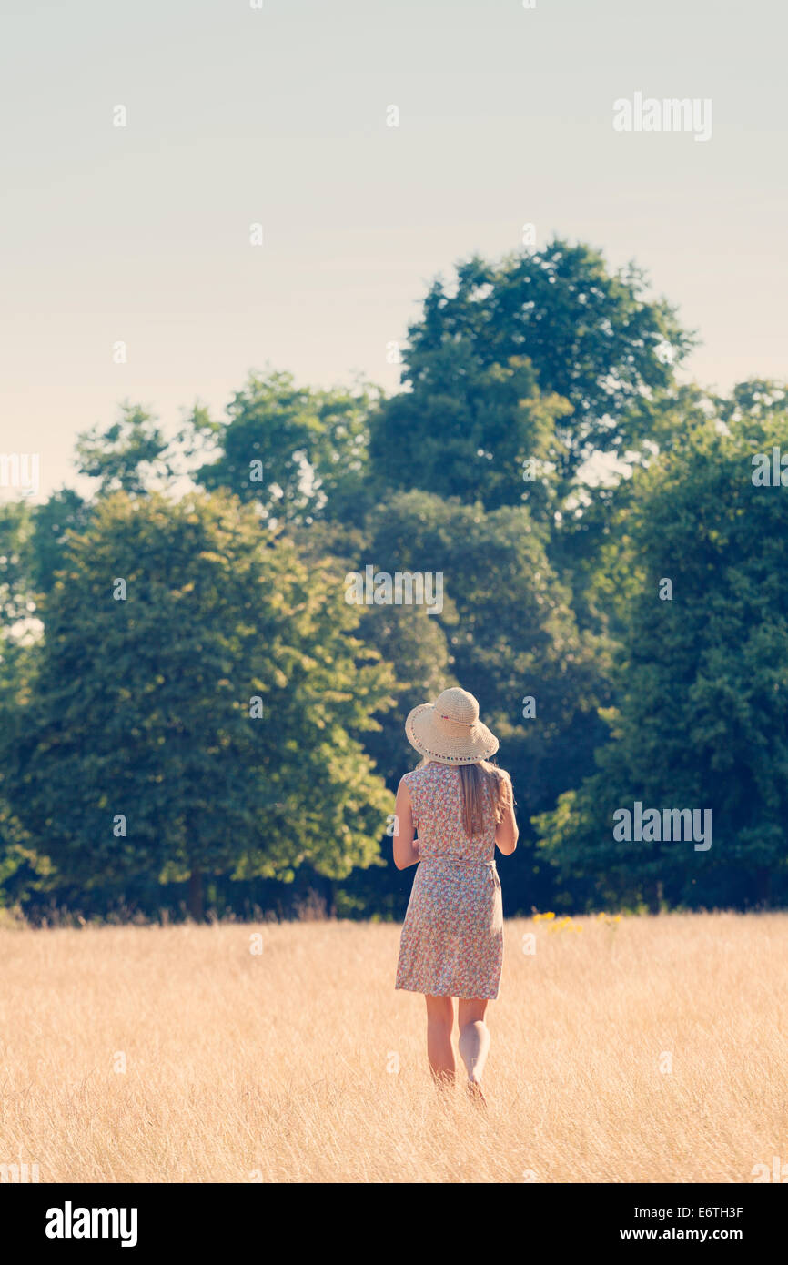 Una joven caminando en un campo de hierba en Hyde Park, Londres, en el verano de inglés Foto de stock
