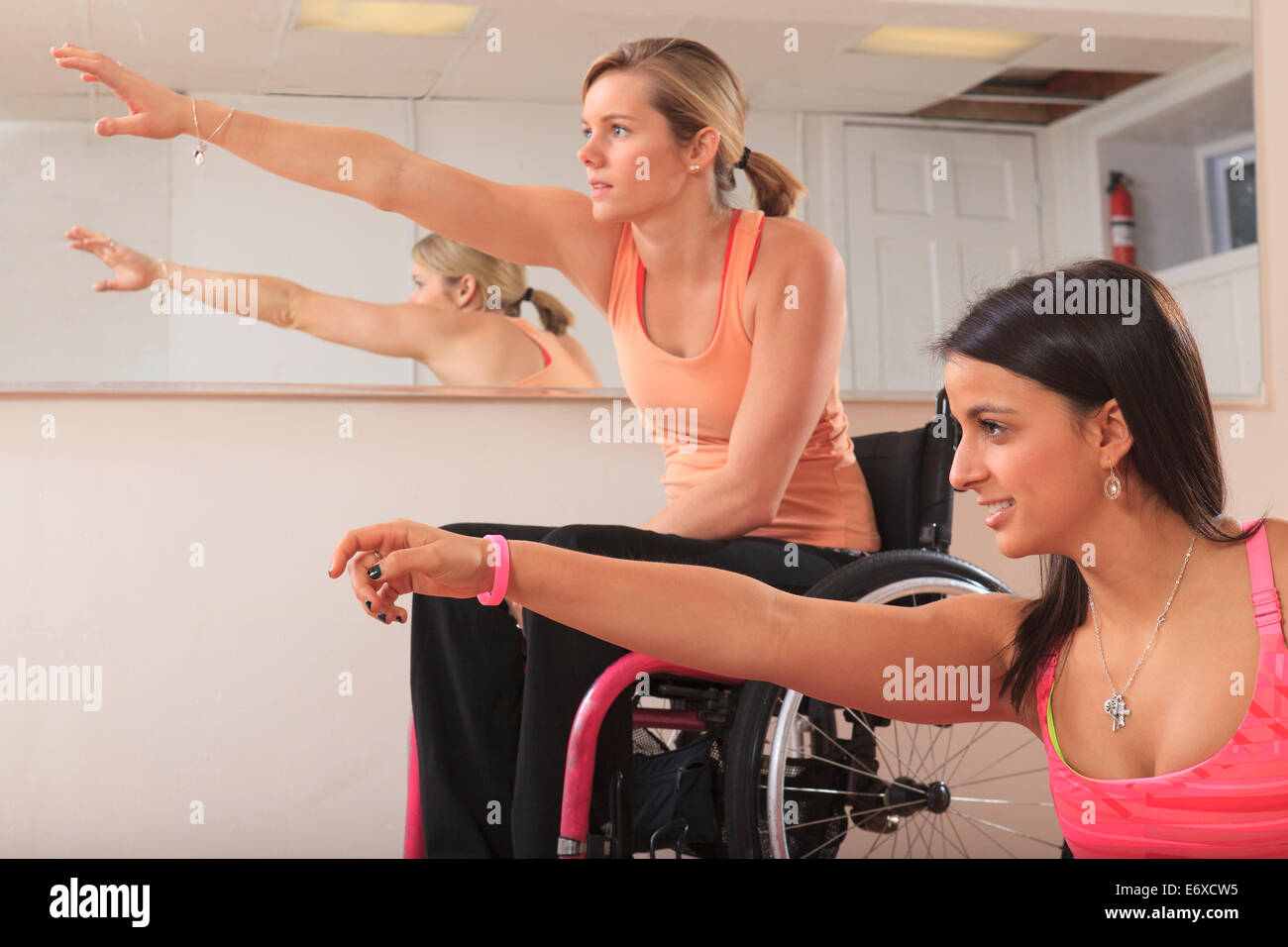Las mujeres jóvenes con lesiones de la médula espinal estiramiento en un estudio de yoga Foto de stock