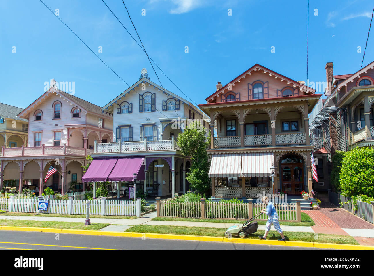 Ee.Uu.,Nueva Jersey,Cape May, casas victorianas y persona segar césped delantero. Foto de stock