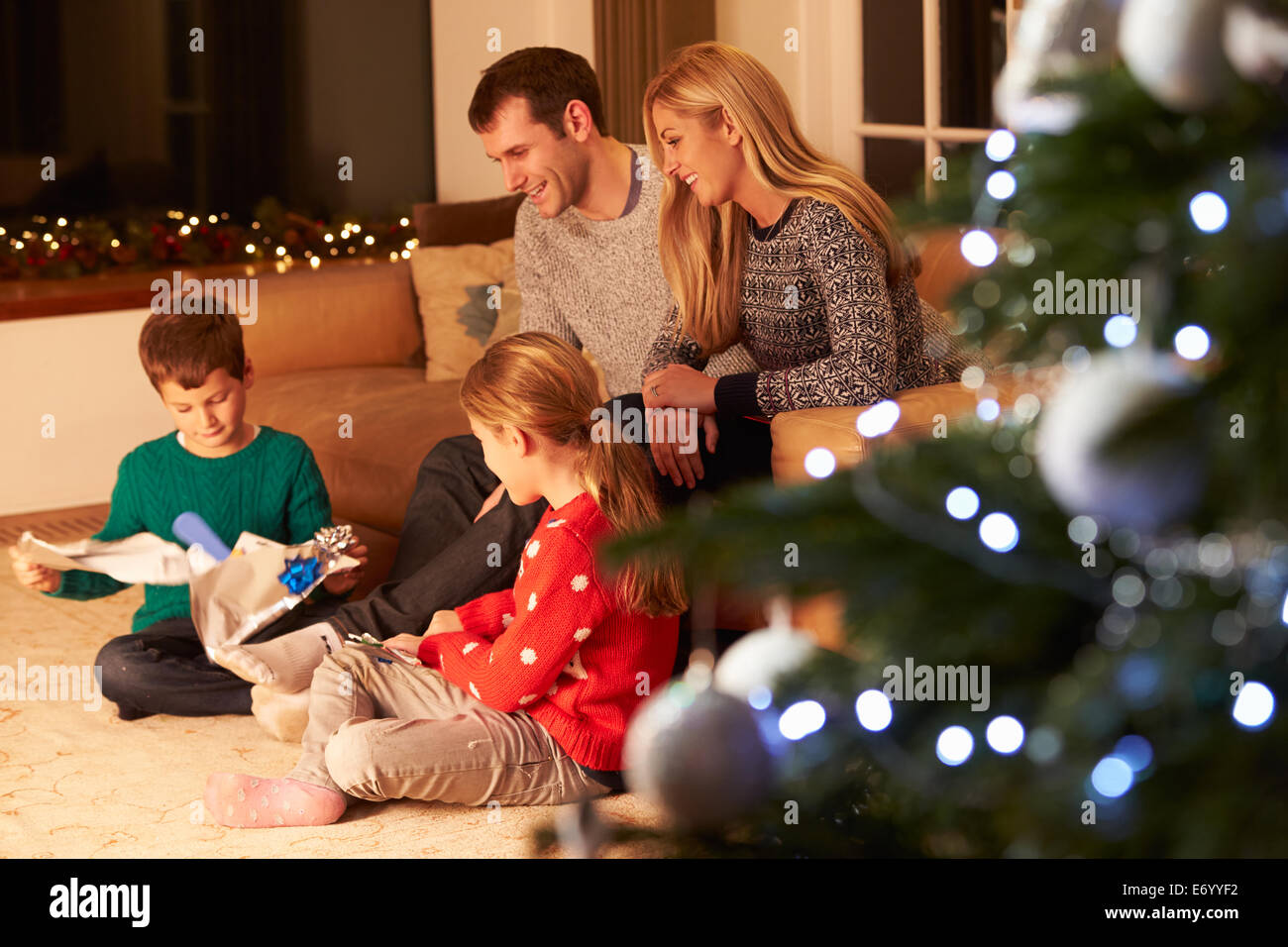 Familia desenvolviendo regalos por árbol de Navidad Foto de stock