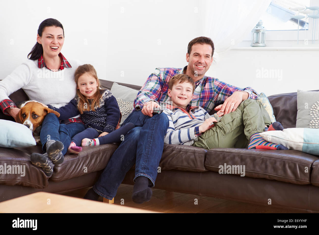 Familia relajante adentro viendo televisión juntos Foto de stock