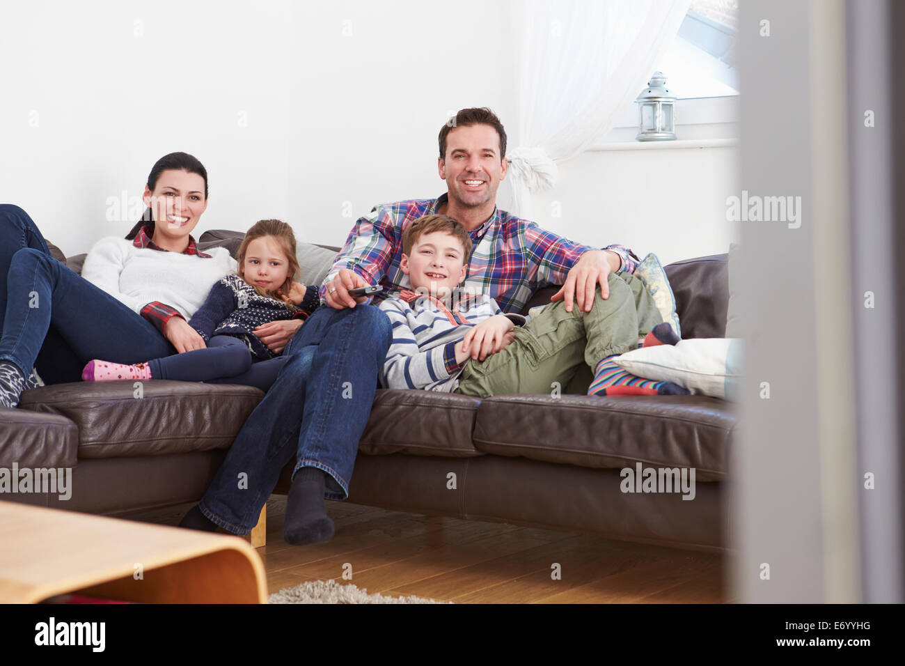 Familia relajante adentro viendo televisión juntos Foto de stock