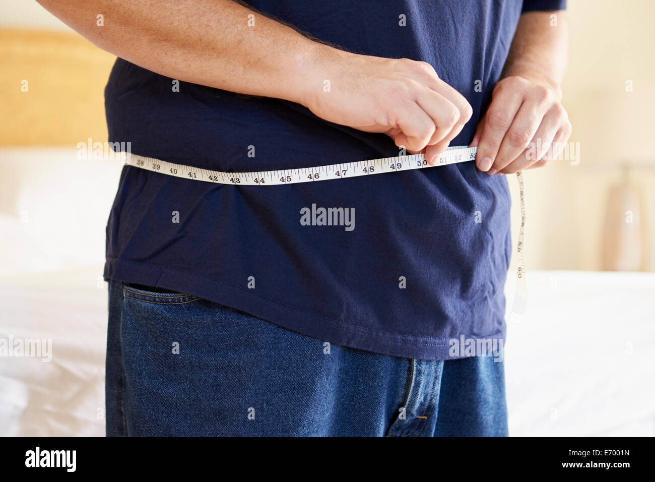 Primer plano de un hombre con sobrepeso midiendo la cintura Foto de stock