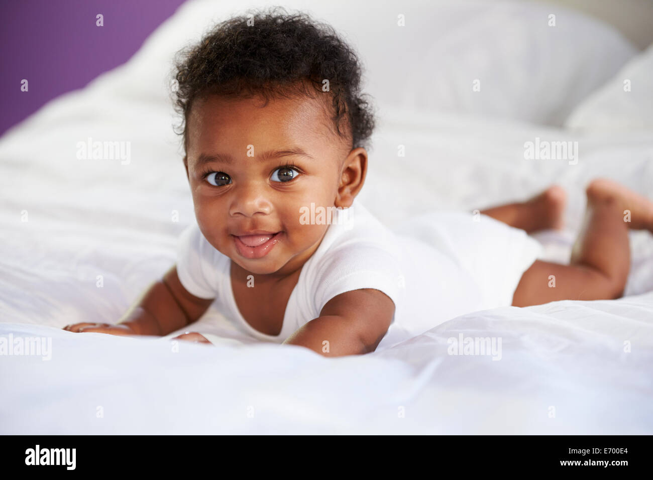 Lindo bebé acostado sobre el estómago en la cama con los padres Foto de stock