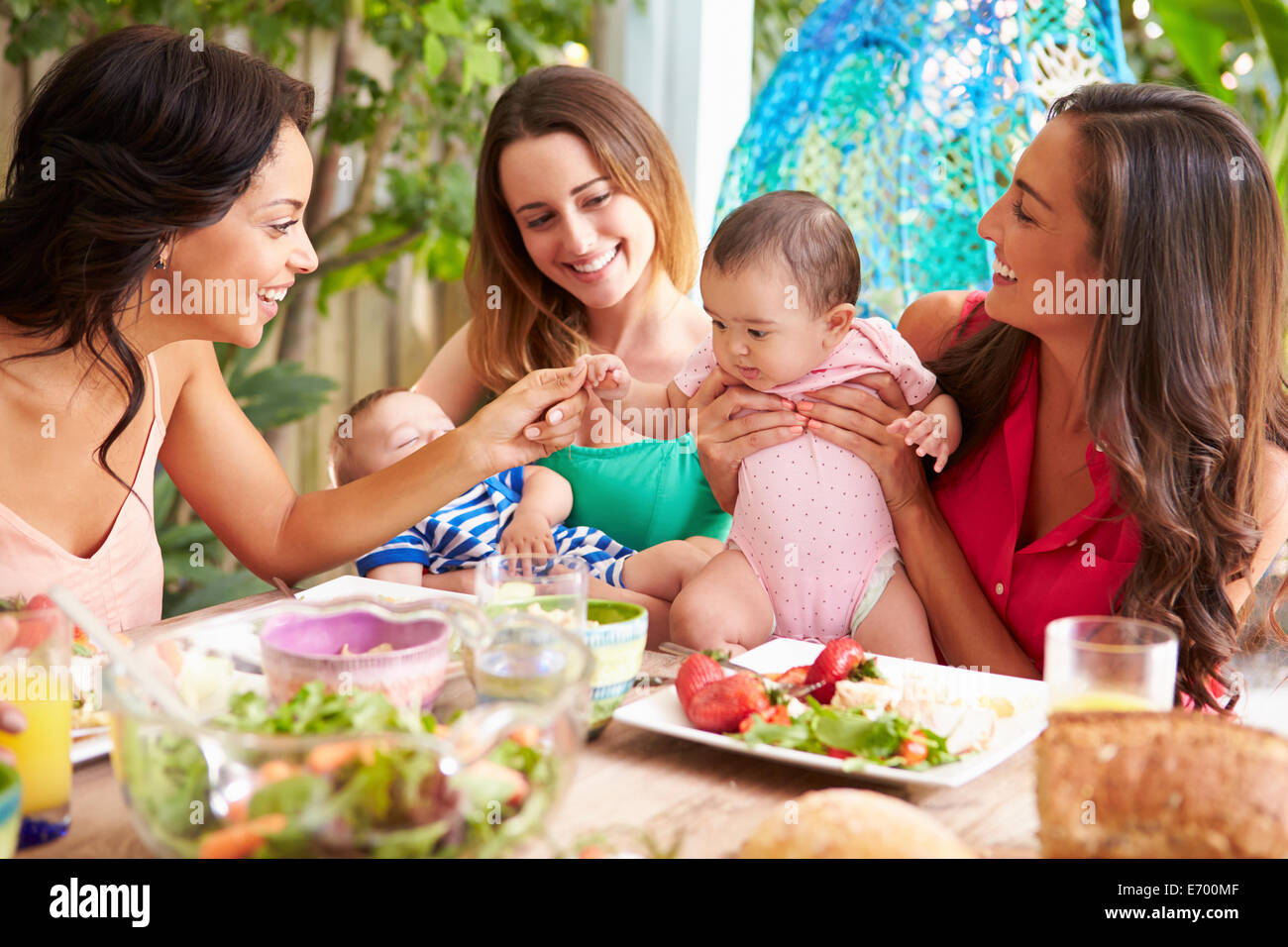 Grupo de madres con bebés disfrutando de comida al aire libre en el hogar Foto de stock